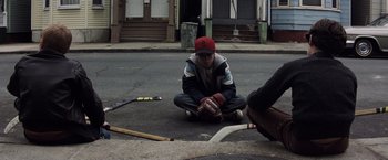 Movie still from “Mystic River” (2003), directed by Clint Eastwood – A man sitting on the ground next to a hockey stick; Wide shot, High angle