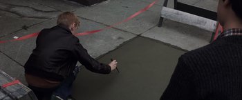 Movie still from “Mystic River” (2003), directed by Clint Eastwood – A man is cutting a red ribbon on the sidewalk; Wide shot, High angle