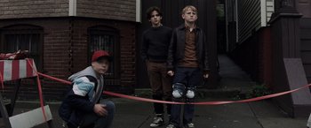 Movie still from “Mystic River” (2003), directed by Clint Eastwood – Three young men standing in front of a red ribbon; Wide shot, Low angle