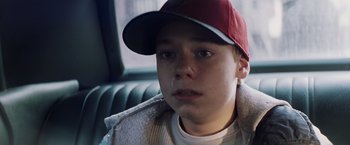 Movie still from “Mystic River” (2003), directed by Clint Eastwood – A young boy with a red hat is sitting in the back of a car; Close Up shot, Over the shoulder angle