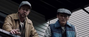 Movie still from “Mystic River” (2003), directed by Clint Eastwood – Two men standing next to each other in front of a building; Medium shot, Low angle