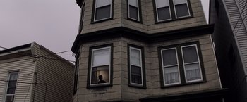 Movie still from “Mystic River” (2003), directed by Clint Eastwood – A person looking out of a window on a building; Extreme Wide shot, Low angle