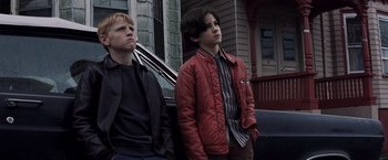 Movie still from “Mystic River” (2003), directed by Clint Eastwood – Two young men standing next to each other in front of a house; Medium shot, Low angle