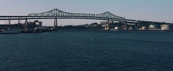 Movie still from “Mystic River” (2003), directed by Clint Eastwood – A boat floating on a body of water near a bridge; Extreme Wide shot, High angle