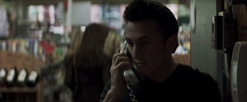 Movie still from “Mystic River” (2003), directed by Clint Eastwood – A man talking on a phone while wearing a black t - shirt; Close Up shot, Low angle
