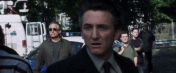 Movie still from “Mystic River” (2003), directed by Clint Eastwood – A person wearing a suit and tie; Close Up shot, Over the shoulder angle