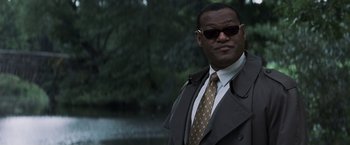 Movie still from “Mystic River” (2003), directed by Clint Eastwood – A man in a suit and tie standing in front of a body of water; Close Up shot, Low angle