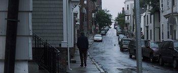 Movie still from “Mystic River” (2003), directed by Clint Eastwood – A man walking down the street in the rain; Wide shot, High angle