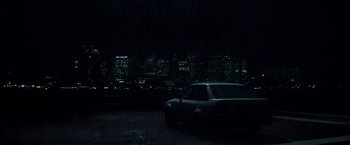 Movie still from “Mystic River” (2003), directed by Clint Eastwood – A car parked in a parking lot in front of a city skyline at night; Extreme Wide shot, Low angle