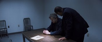 Movie still from “Mystic River” (2003), directed by Clint Eastwood – Two men sitting at a table looking at a piece of paper; Medium shot, Over the shoulder angle