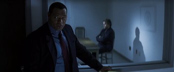 Movie still from “Mystic River” (2003), directed by Clint Eastwood – A man in a suit and tie standing in a room; Medium shot, Over the shoulder angle