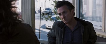 Movie still from “Mystic River” (2003), directed by Clint Eastwood – A person sitting on a bench near a street; Close Up shot, Over the shoulder angle