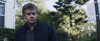 Movie still from “Mystic River” (2003), directed by Clint Eastwood – A man standing in front of some bushes; Medium shot, Low angle