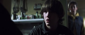 Movie still from “Mystic River” (2003), directed by Clint Eastwood – A young man sitting in a dark room; Close Up shot, Over the shoulder angle