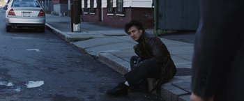 Movie still from “Mystic River” (2003), directed by Clint Eastwood – A man sitting on the side of the street; Medium shot, Low angle