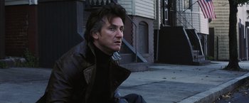 Movie still from “Mystic River” (2003), directed by Clint Eastwood – A man sitting on the ground in front of a building; Close Up shot, Low angle