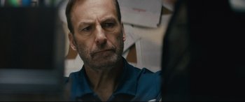 Movie still from “Nobody” (2021), directed by Ilya Naishuller – A person wearing a blue shirt; Close Up shot, Over the shoulder angle