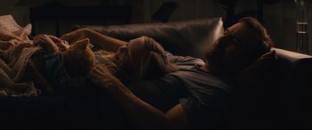 Movie still from “Nobody” (2021), directed by Ilya Naishuller – A man and a woman laying on a couch; Medium shot, Over the shoulder angle