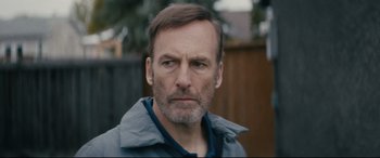 Movie still from “Nobody” (2021), directed by Ilya Naishuller – A person wearing a jacket; Close Up shot, Over the shoulder angle