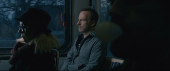 Movie still from “Nobody” (2021), directed by Ilya Naishuller – A man sitting on a train looking out the window; Close Up shot, Over the shoulder angle
