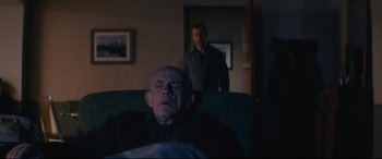 Movie still from “Nobody” (2021), directed by Ilya Naishuller – An older man sleeping in a chair next to a younger man; Medium shot, Over the shoulder angle