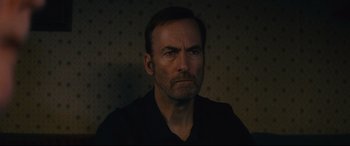 Movie still from “Nobody” (2021), directed by Ilya Naishuller – A person wearing a black shirt; Close Up shot, High angle