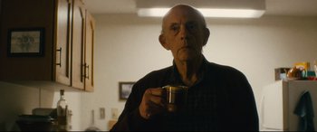 Movie still from “Nobody” (2021), directed by Ilya Naishuller – An older man holding a cup of coffee in his hand; Close Up shot, Low angle