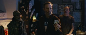 Movie still from “Nobody” (2021), directed by Ilya Naishuller – A man holding a cell phone in his hand; Medium shot, Over the shoulder angle