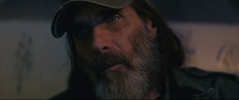 Movie still from “Nobody” (2021), directed by Ilya Naishuller – A man with long hair and a beard wearing a hat; Close Up shot, Low angle