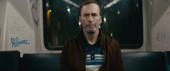 Movie still from “Nobody” (2021), directed by Ilya Naishuller – A person sitting on a bench; Close Up shot, Low angle