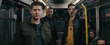 Movie still from “Nobody” (2021), directed by Ilya Naishuller – A group of men standing next to each other on a bus; Medium shot, Low angle