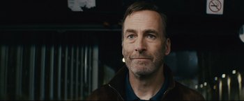 Movie still from “Nobody” (2021), directed by Ilya Naishuller – A person wearing a brown jacket; Close Up shot, Over the shoulder angle