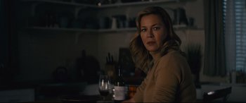 Movie still from “Nobody” (2021), directed by Ilya Naishuller – A woman sitting at a table with a glass of wine; Close Up shot, Over the shoulder angle