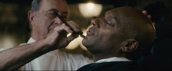 Movie still from “Nobody” (2021), directed by Ilya Naishuller – A man getting his teeth brushed by a barber; Extreme Close Up shot, Over the shoulder angle