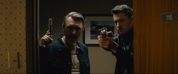 Movie still from “Nobody” (2021), directed by Ilya Naishuller – Two men are holding guns in a room; Medium shot, Low angle