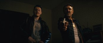 Movie still from “Nobody” (2021), directed by Ilya Naishuller – Two men are playing a video game in a dark room; Medium shot, Low angle
