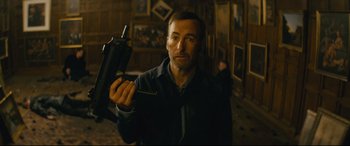 Movie still from “Nobody” (2021), directed by Ilya Naishuller – A man holding a cell phone in his hand; Medium shot, Low angle