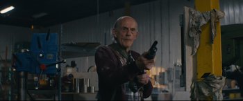 Movie still from “Nobody” (2021), directed by Ilya Naishuller – An older man holding a gun in a room; Medium shot, Low angle