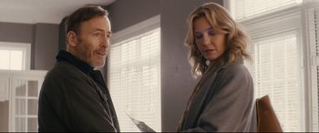 Movie still from “Nobody” (2021), directed by Ilya Naishuller – A man and a woman standing next to each other in front of a window; Medium shot, Over the shoulder angle