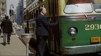 Movie still from “North by Northwest” (1959), directed by Alfred Hitchcock – A man standing next to a green and yellow bus; Wide shot, Low angle