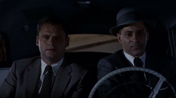 Movie still from “North by Northwest” (1959), directed by Alfred Hitchcock – Two men sitting in a car wearing suits and hats; Close Up shot, Low angle