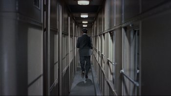 Movie still from “North by Northwest” (1959), directed by Alfred Hitchcock – A man walking down a long hallway in a suit; Wide shot, High angle