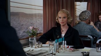 Movie still from “North by Northwest” (1959), directed by Alfred Hitchcock – A woman sitting at a dinner table in front of the ocean; Medium shot, High angle
