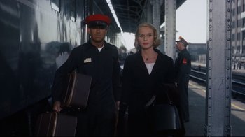 Movie still from “North by Northwest” (1959), directed by Alfred Hitchcock – A man and a woman walking down a train platform holding suitcases; Medium shot, Low angle