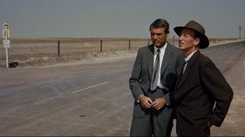 Movie still from “North by Northwest” (1959), directed by Alfred Hitchcock – Two men standing on the side of a road; Medium shot, Over the shoulder angle