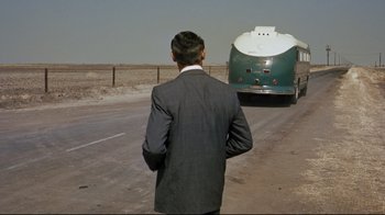 Movie still from “North by Northwest” (1959), directed by Alfred Hitchcock – A man standing on the side of a road next to a tanker truck; Wide shot, Over the shoulder angle