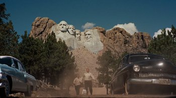 Movie still from “North by Northwest” (1959), directed by Alfred Hitchcock – Two men standing in front of a car and a mountain; Extreme Wide shot, Low angle