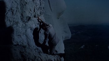 Movie still from “North by Northwest” (1959), directed by Alfred Hitchcock – A man climbing up a rock wall at night; Wide shot, Low angle