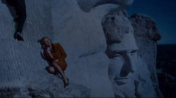 Movie still from “North by Northwest” (1959), directed by Alfred Hitchcock – A woman sitting on the side of a rock face; Wide shot, Low angle