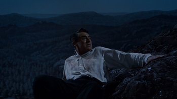 Movie still from “North by Northwest” (1959), directed by Alfred Hitchcock – A man sitting on top of a mountain at night; Medium shot, High angle